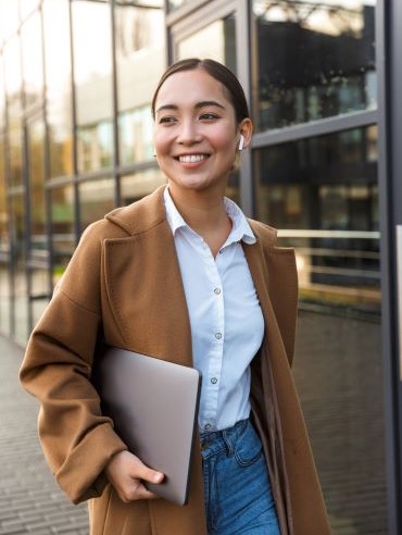 Asian woman holding a laptop and representing project management in the Stellar Career Accelerator program